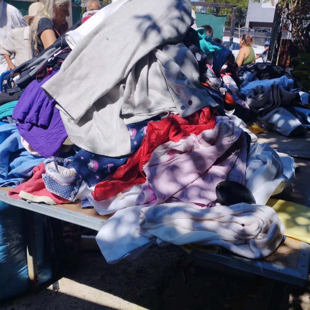 Vecinas y vecinos retirando mercadería y ropa en el comedor