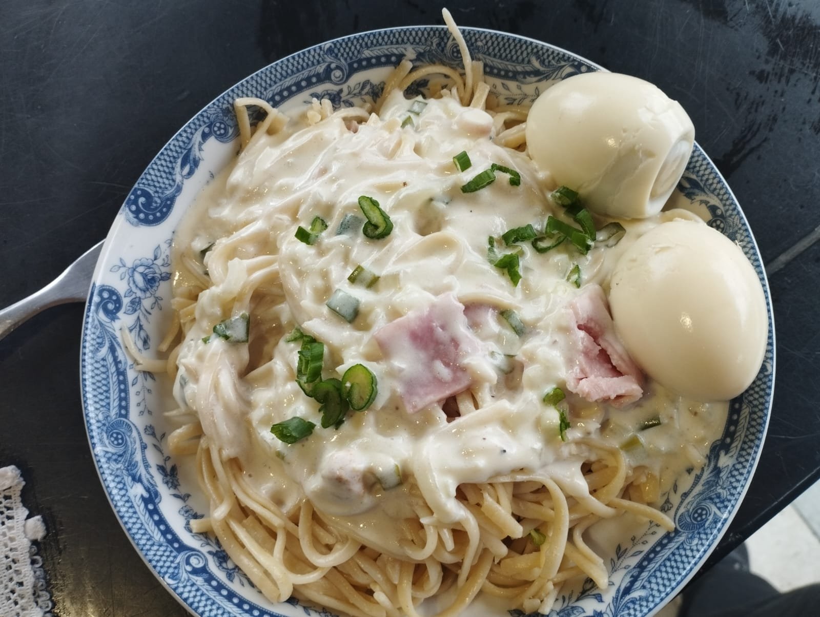 Plato servido de tallarines con salsa blanca y huevo duro