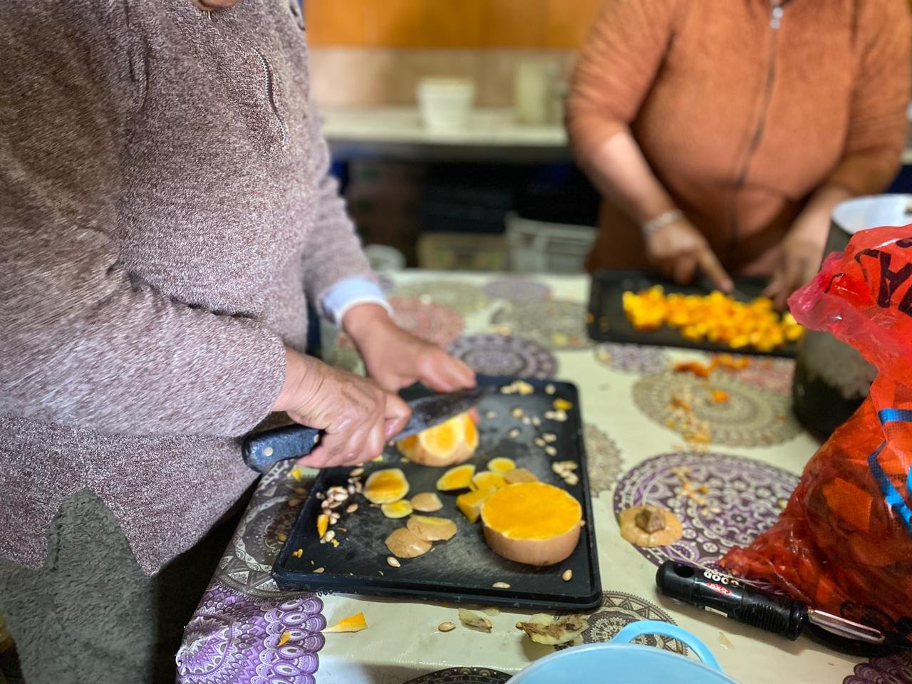 Dos voluntarias cortando zapallo para la comida del día